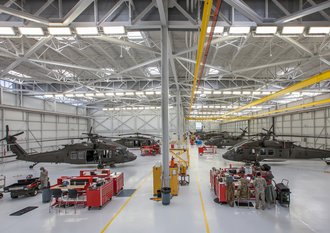 A large hangar with a lot of helicopters in it