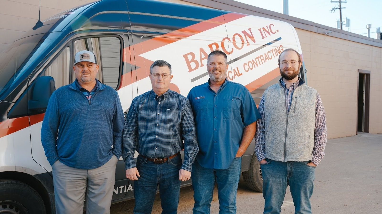 A group of men are standing in front of a van.