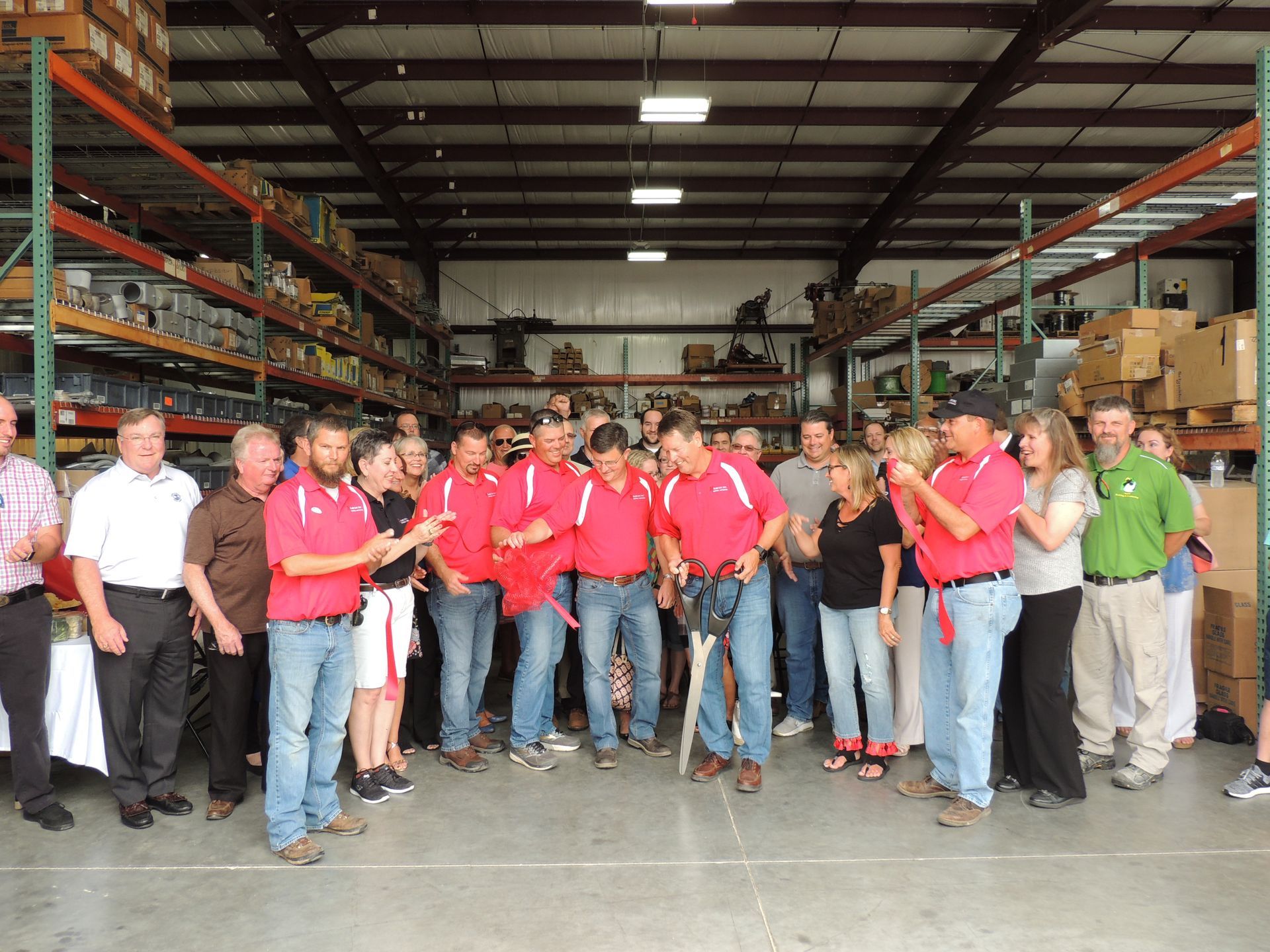 A group of people in red shirts are standing in a warehouse.