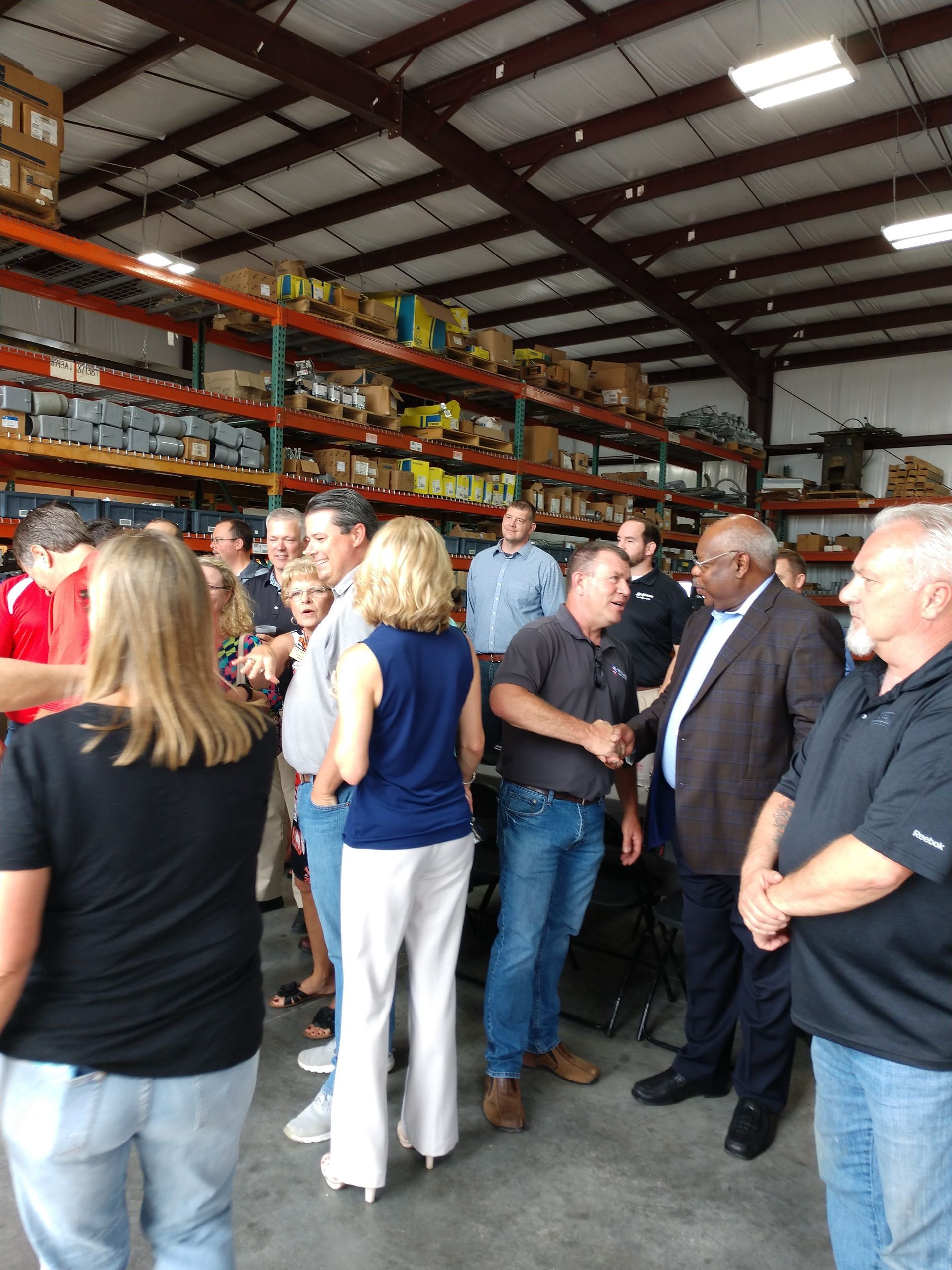 A group of people are standing in a warehouse talking to each other