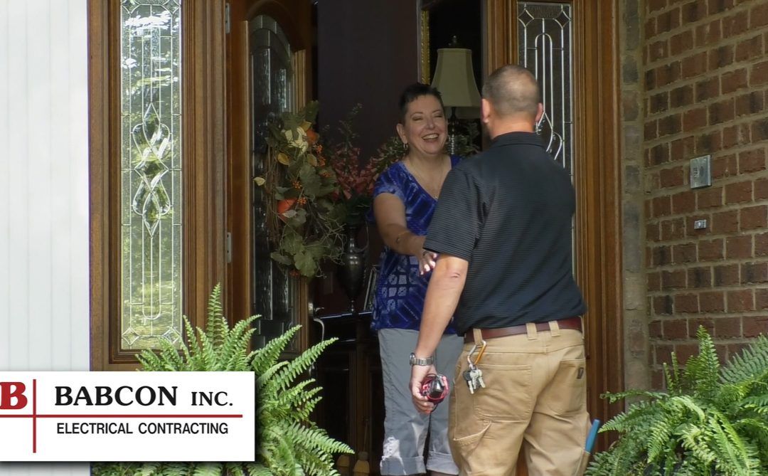 A man and woman are standing in front of a babcon inc. sign