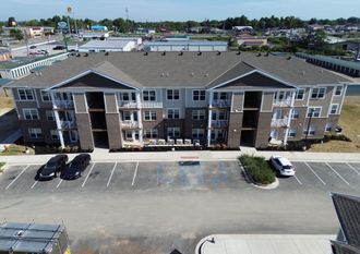 An aerial view of a large apartment building with cars parked in front of it.