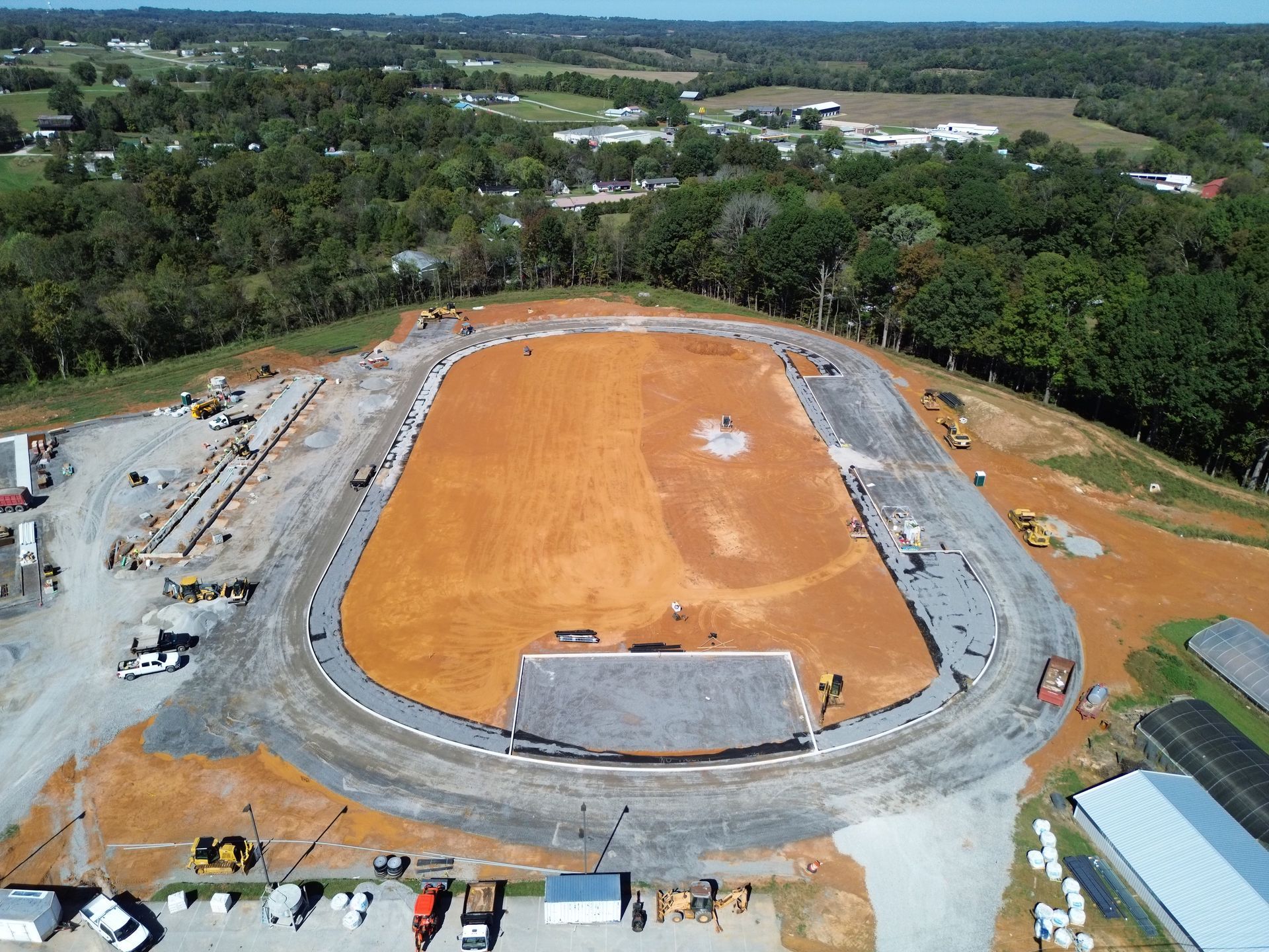 An aerial view of a race track under construction surrounded by trees.