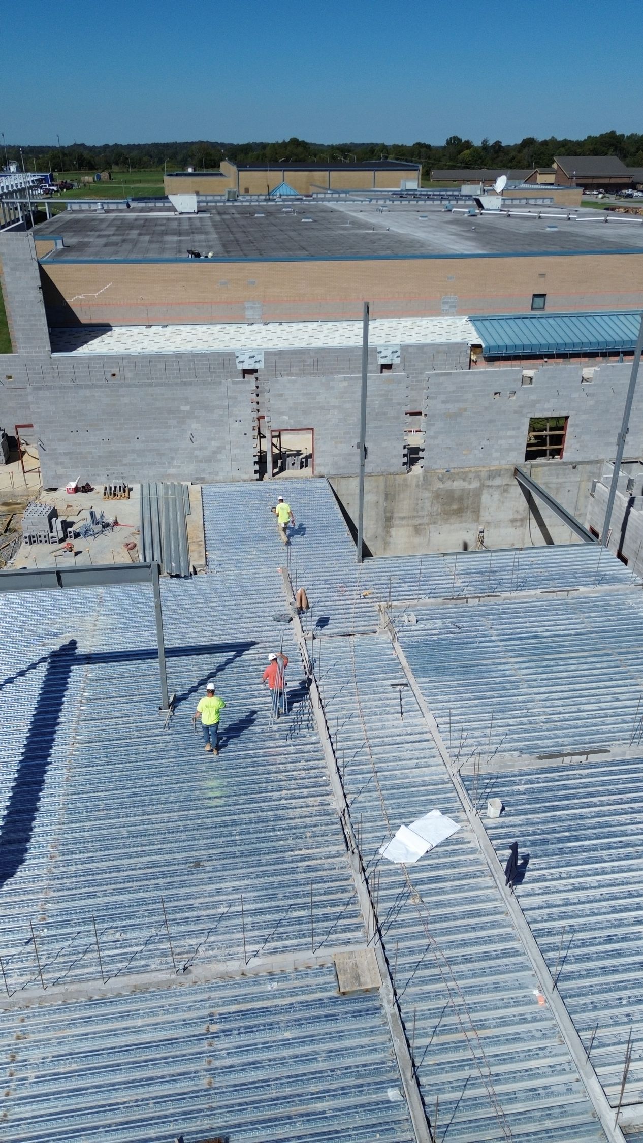 An aerial view of a building under construction with workers on the roof.