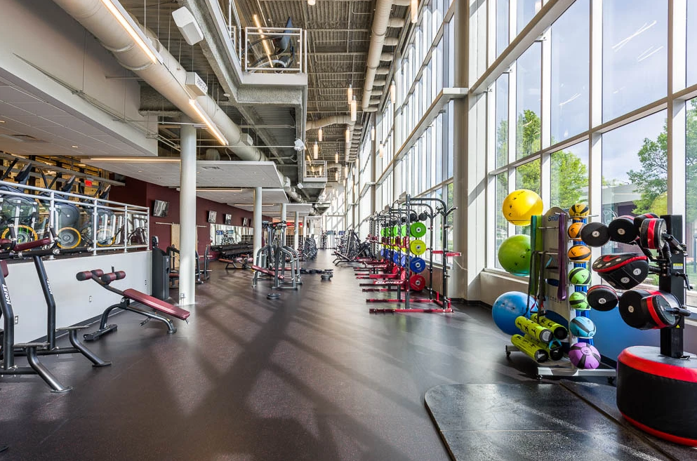 A large gym with a lot of equipment and a lot of windows.