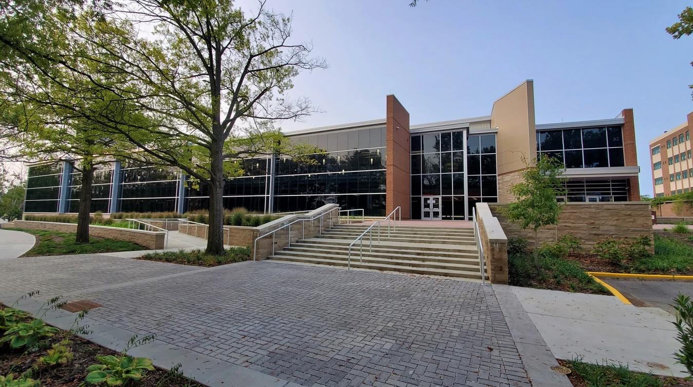 A large building with stairs leading up to it and trees in front of it.