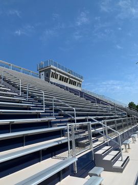 A stadium filled with empty bleachers on a sunny day.