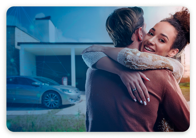 Um homem e uma mulher estão se abraçando em frente a uma casa e um carro.