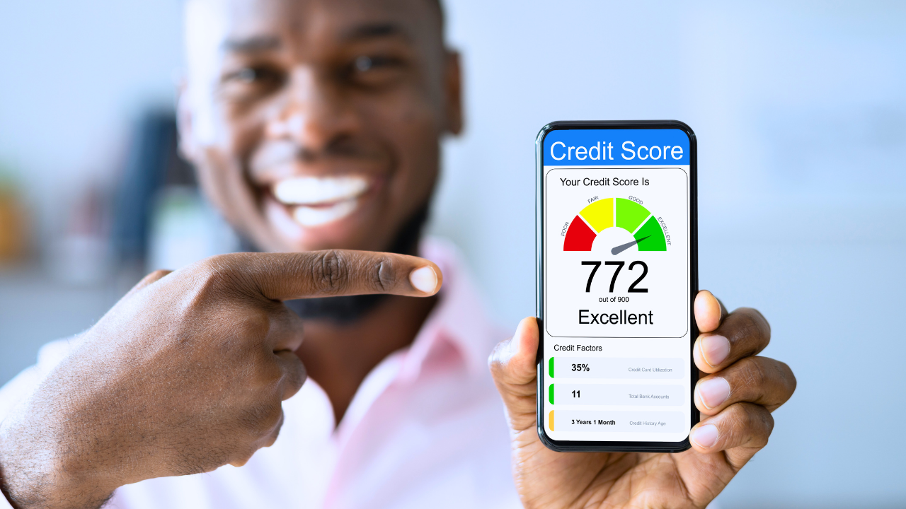 A man is holding a cell phone with a credit score of 772.