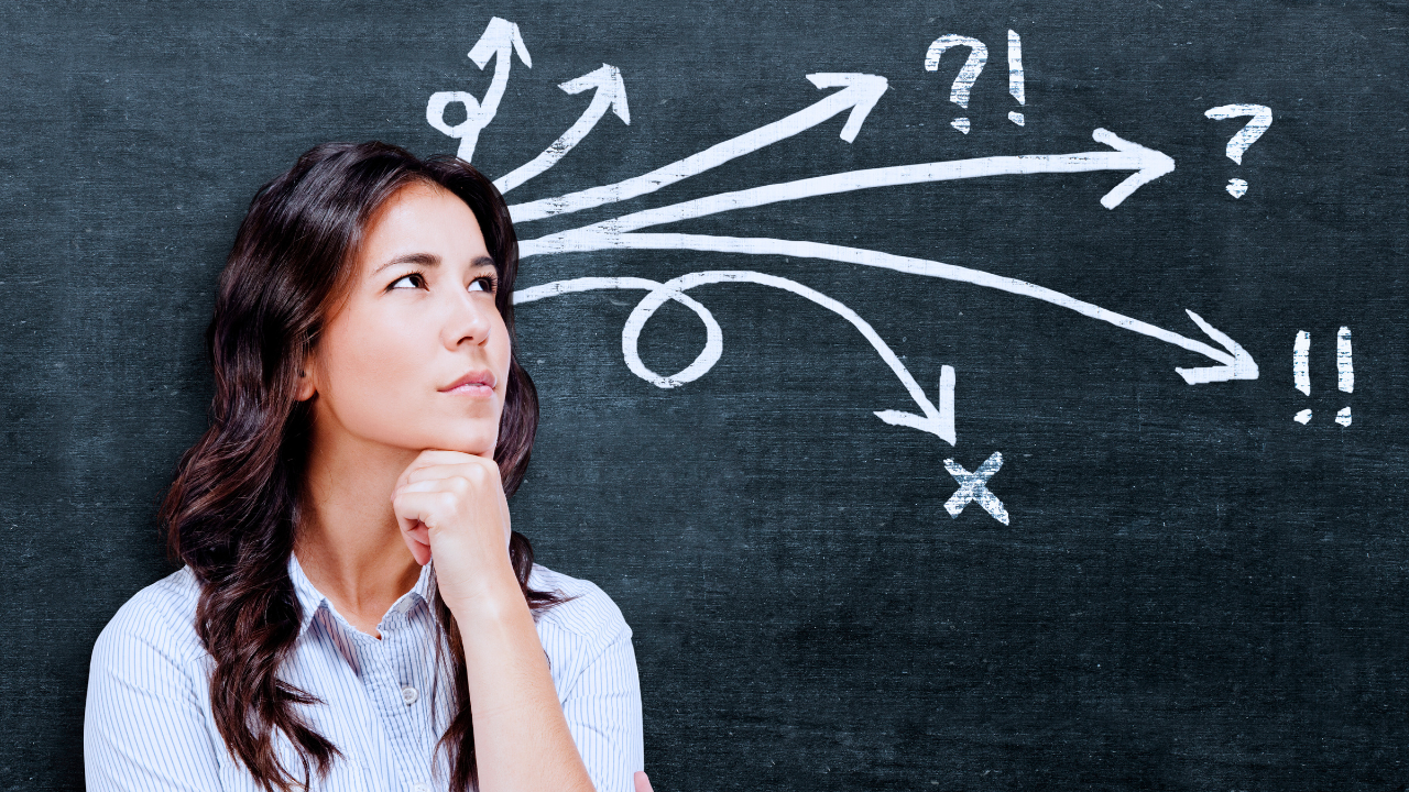 A woman is standing in front of a blackboard with arrows pointing in different directions.