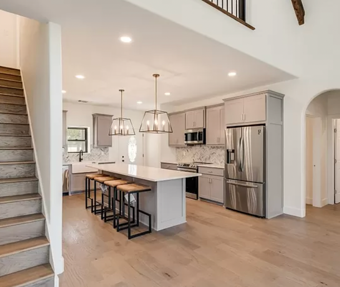 Modern kitchen with island, stainless steel appliances, and wooden flooring.