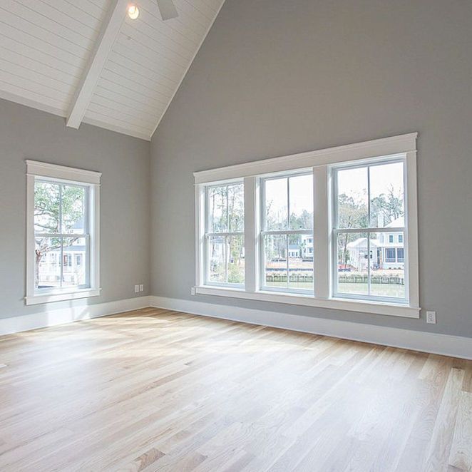 Empty room with hardwood floors, gray walls, white trim, and large windows.