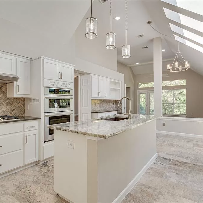 Bright, modern kitchen with white cabinets, island, and appliances. Skylights illuminate the space.