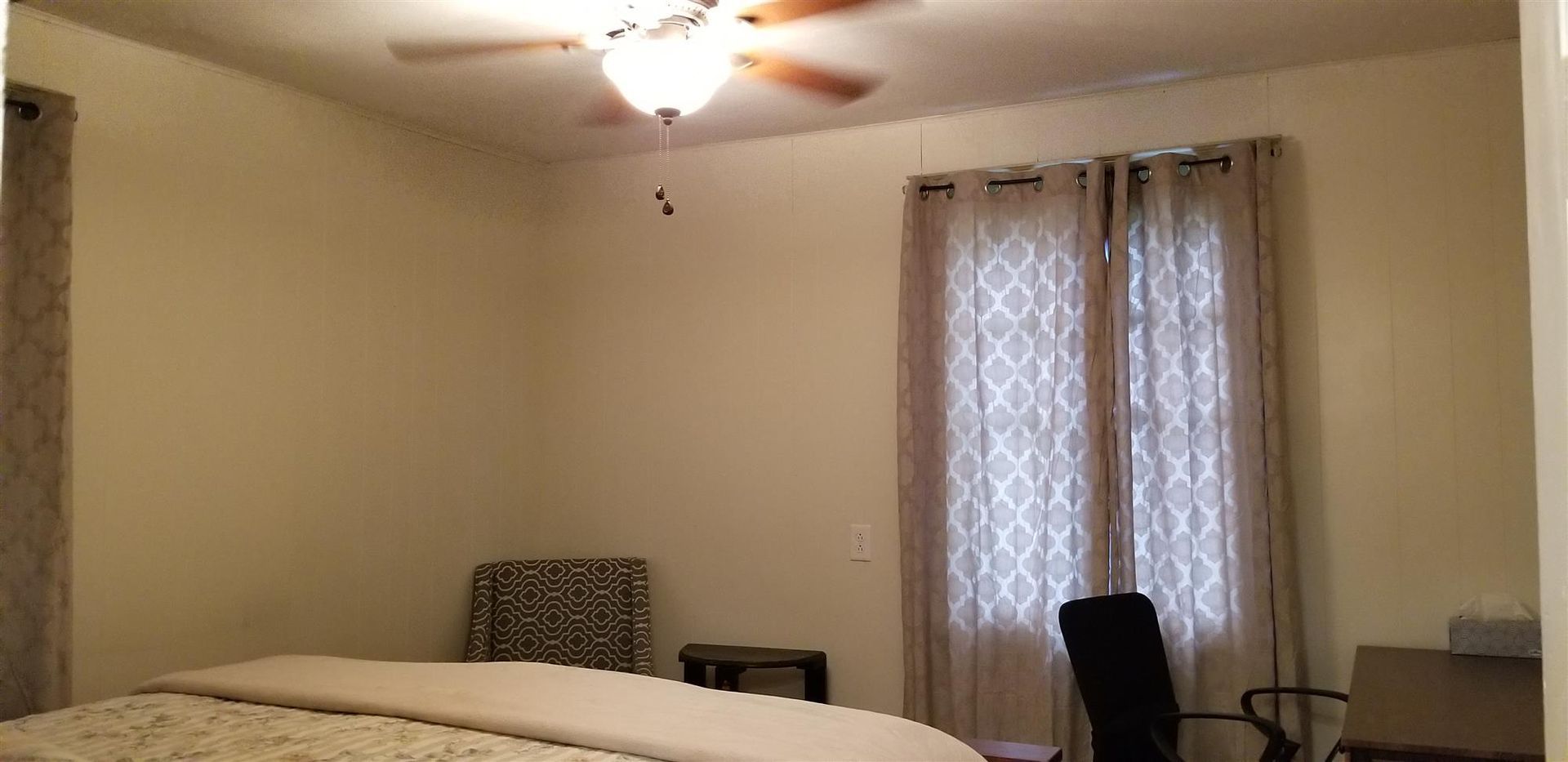 A bedroom with a bed , chair , and ceiling fan.