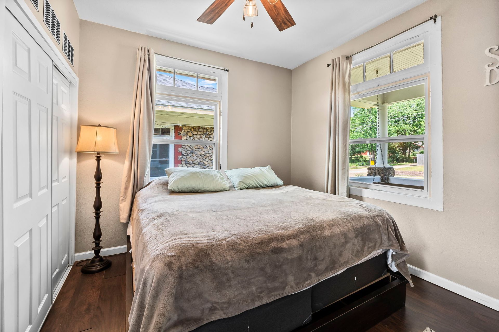 A bedroom with a bed , lamp , and ceiling fan.