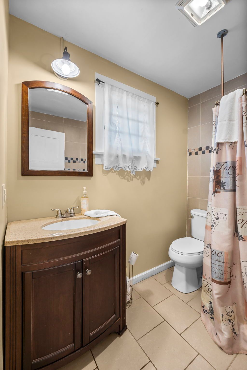 a bathroom with a sink , toilet , mirror and shower curtain .