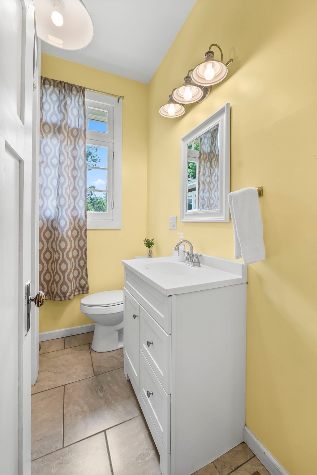 a bathroom with yellow walls , a sink , toilet and mirror .