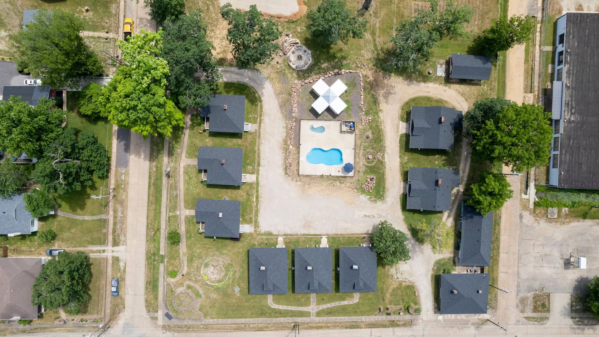 An aerial view of a residential area with a swimming pool in the middle.