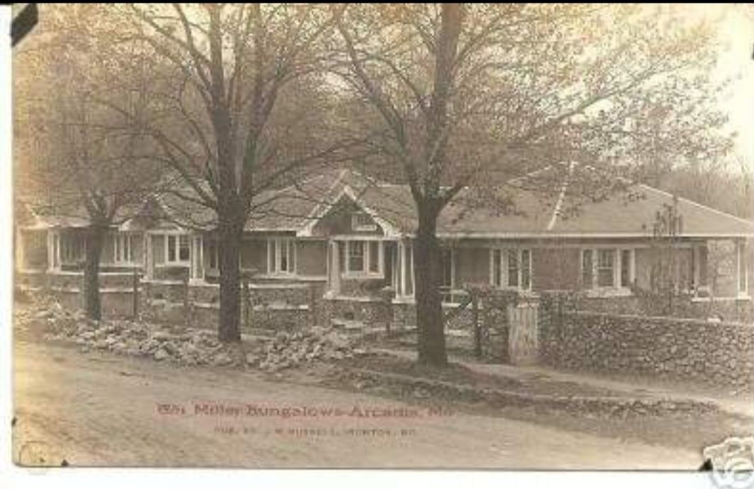 A black and white photo of a house with trees in front of it