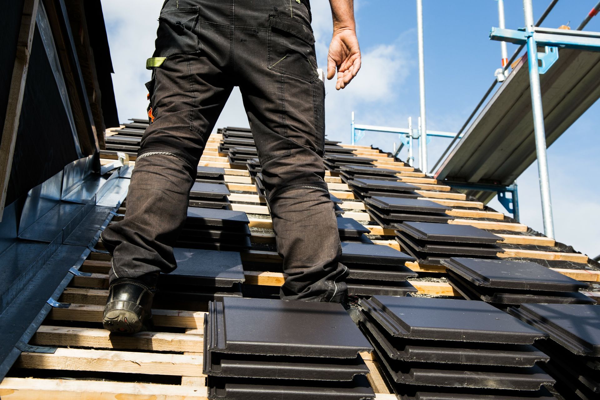 A man is standing on top of a roof covered in tiles.