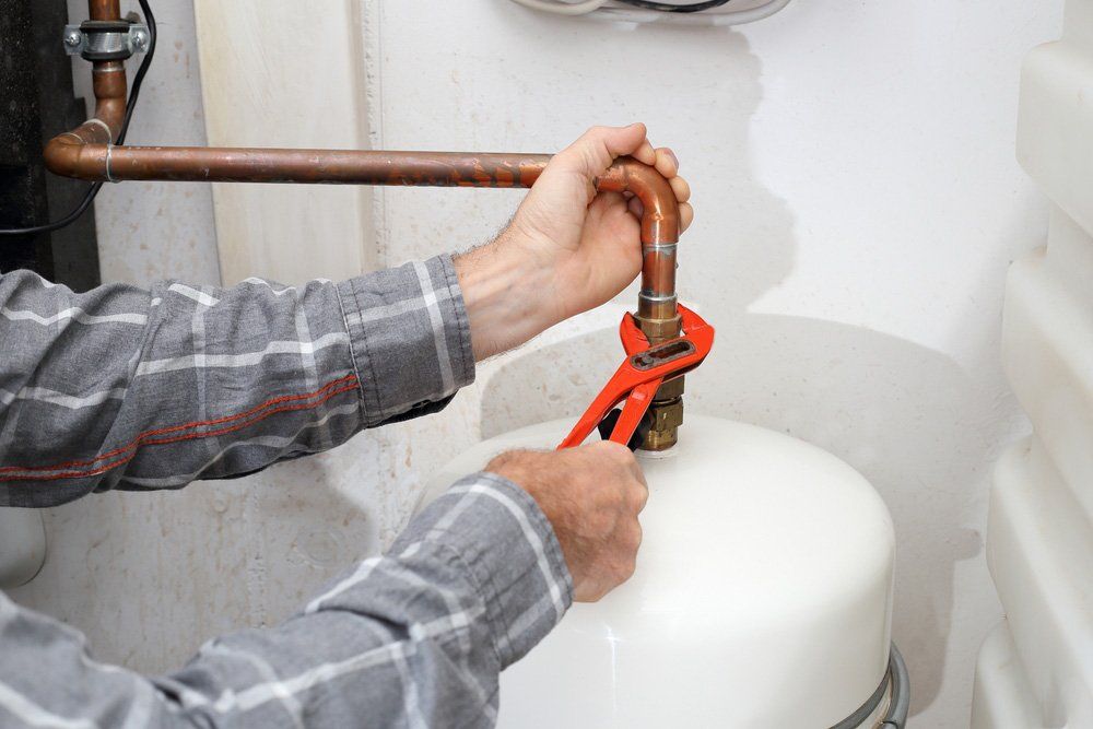 A Man is Fixing a Water Heater With a Wrench — Sidney & Richardson In  Ballina, NSW