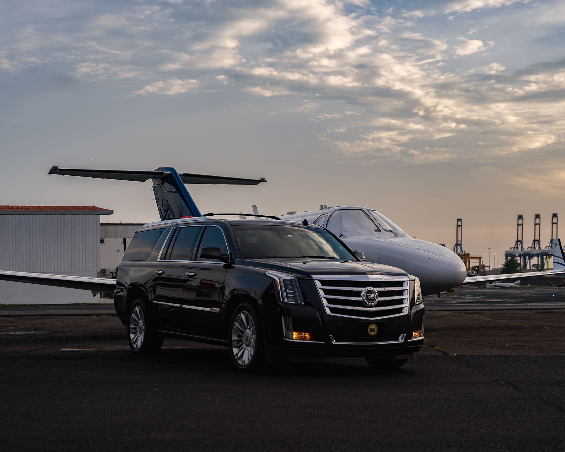 Un todoterreno negro está aparcado al lado de un jet privado.