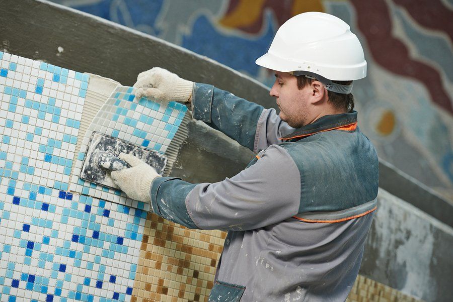 worker installing pool tile