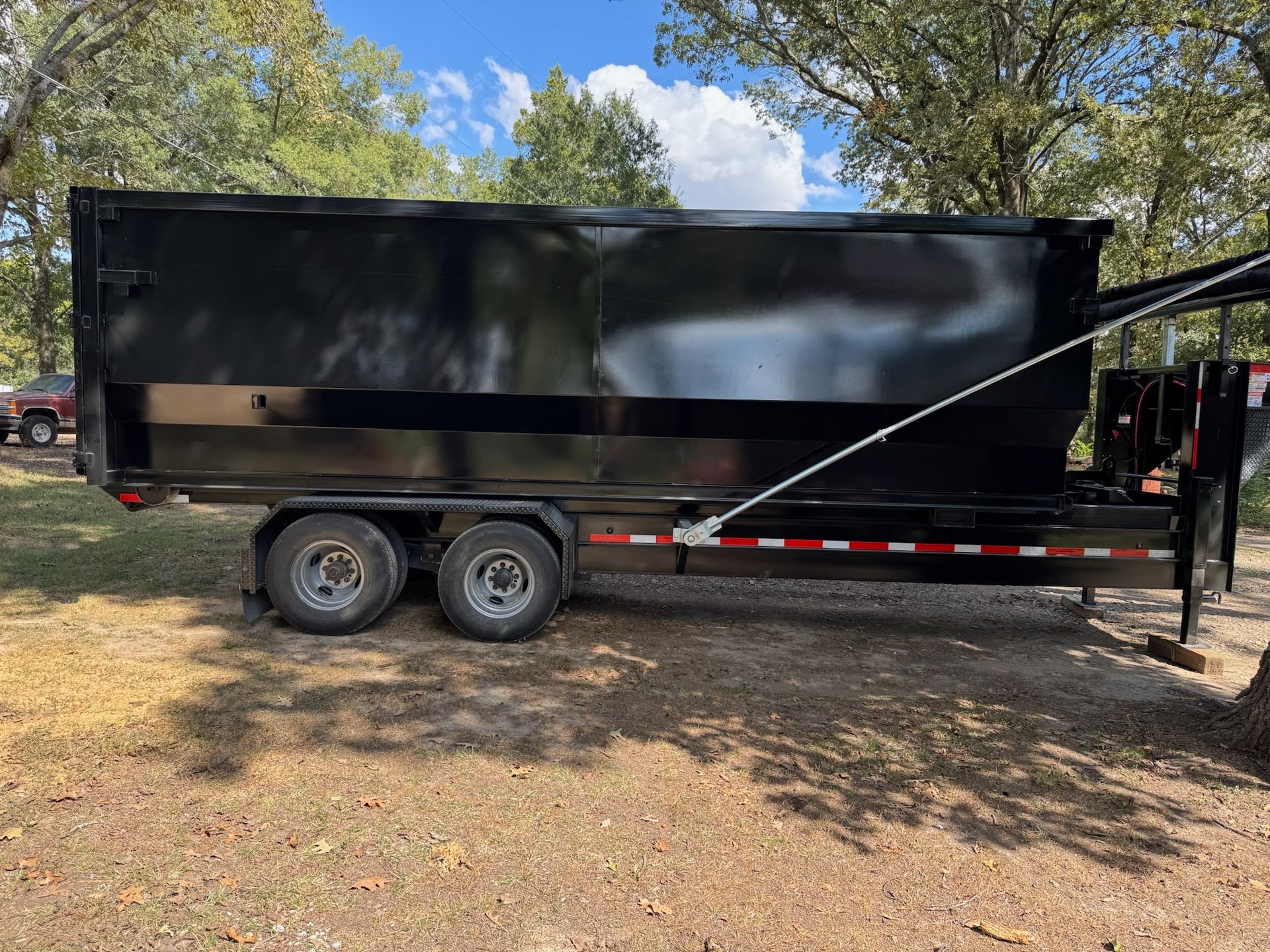 Blue construction dumpster overflowing with drywall, in front of houses under construction.