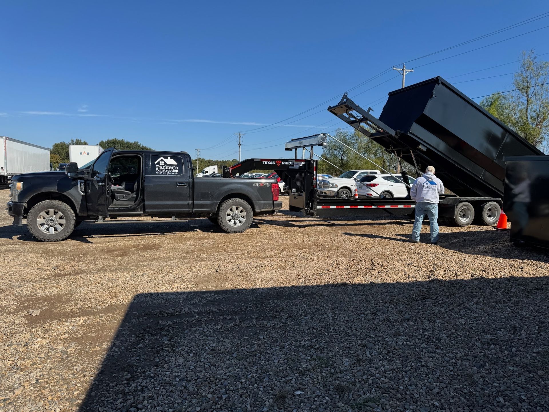 Yellow dumpster, filled with debris, on asphalt, roadside setting, cloudy sky.