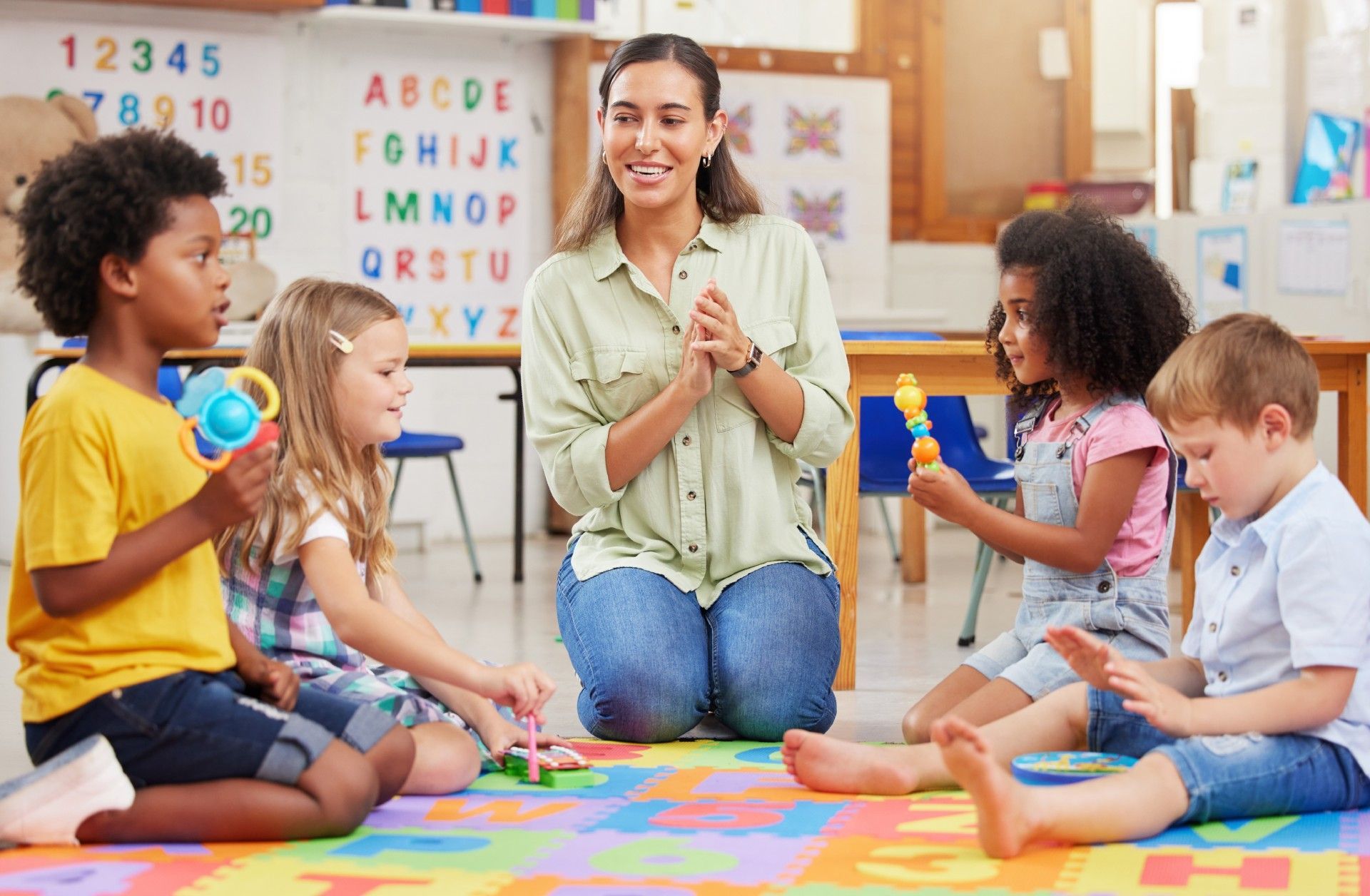 A group of children are sitting on the floor in a classroom with a teacher.