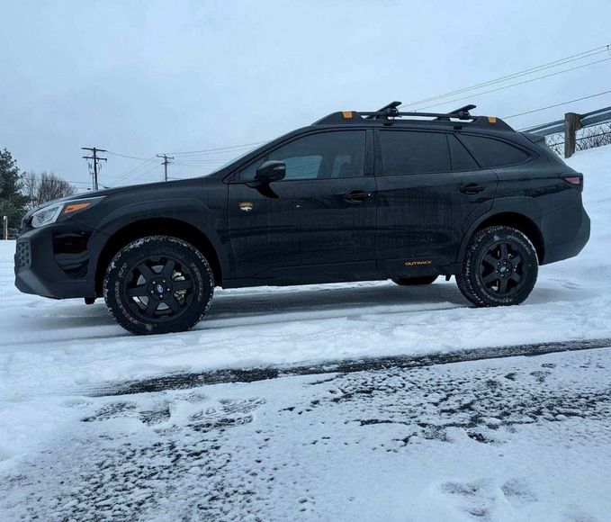 A black suv is parked in the snow on a snowy road.