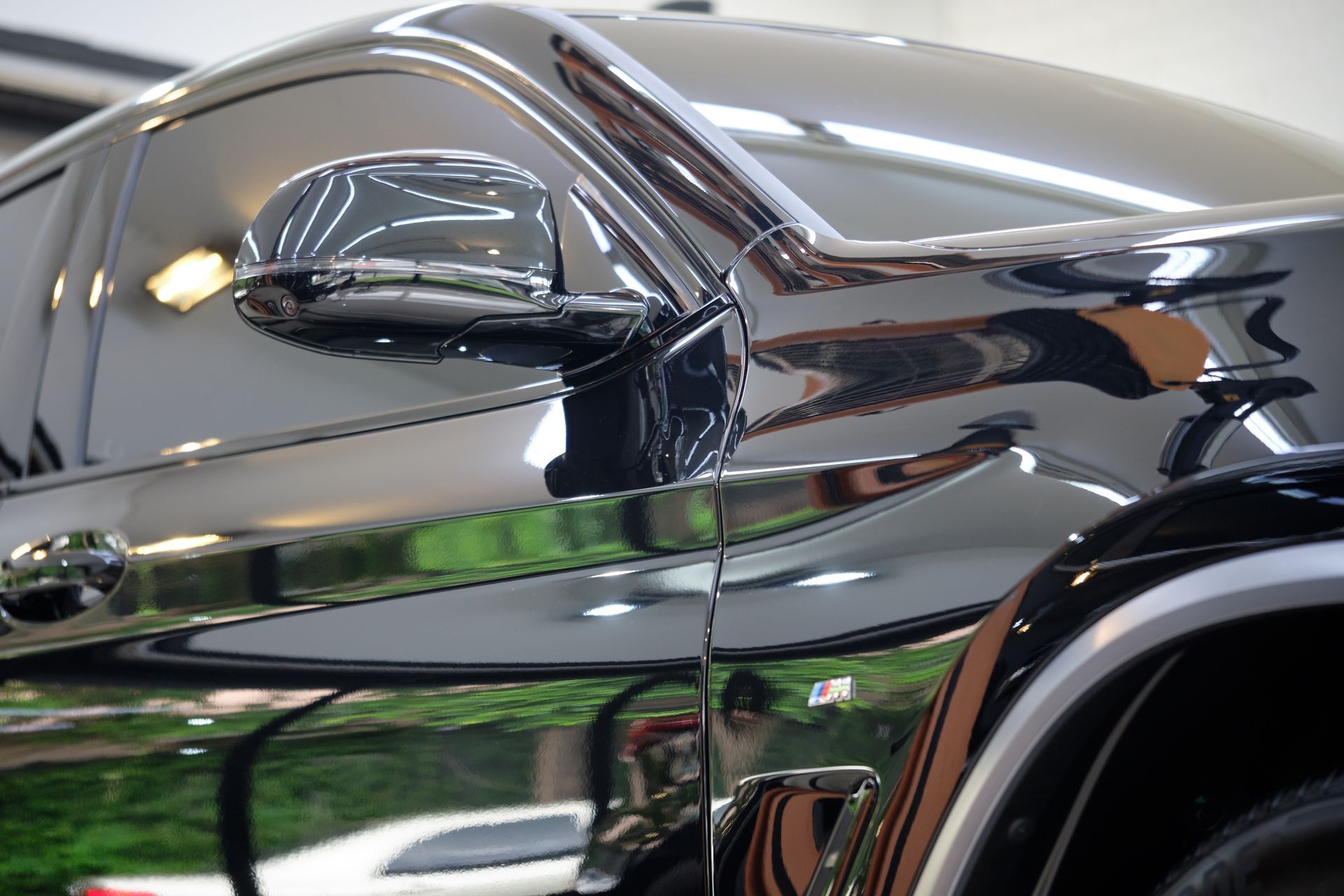 A close up of a black car with a reflection of a person in the mirror.