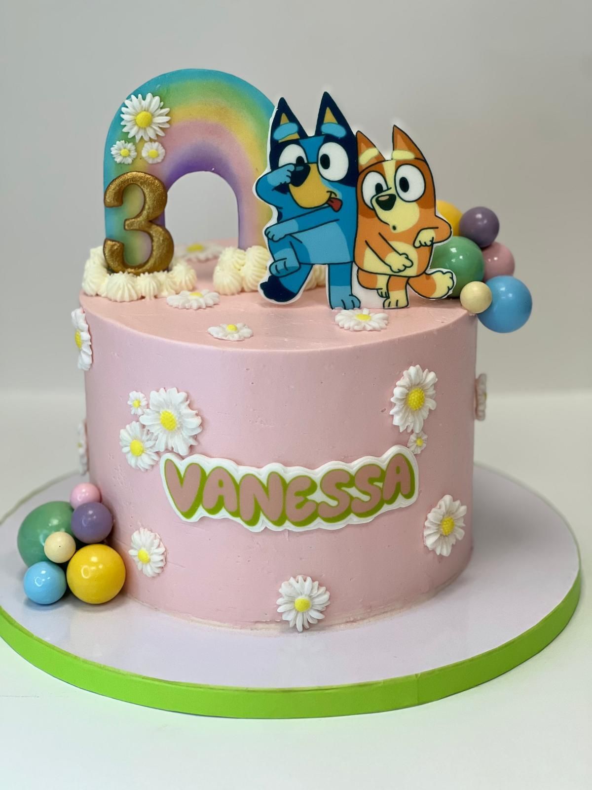 Torta rosa decorata con fiori, farfalle e due fate in cima.