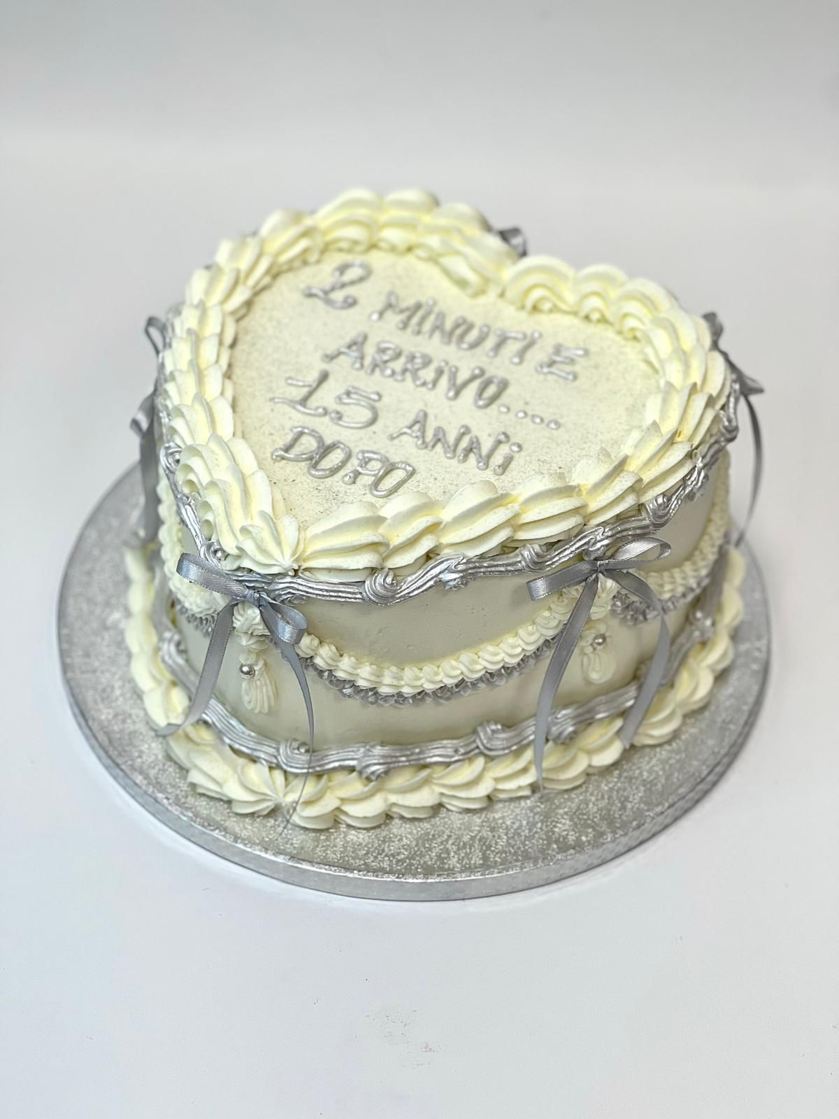 Torta a forma di cuore con glassa bianca, ghirlanda argentata e scritta