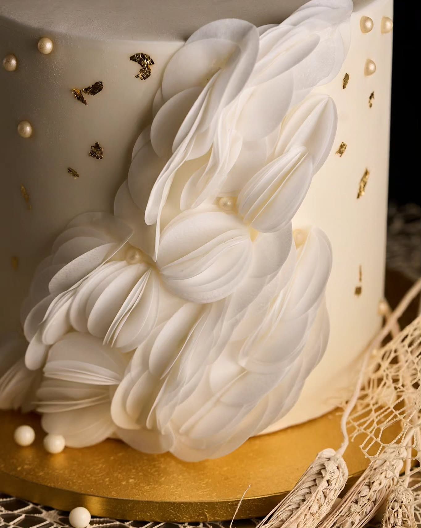Torta bianca con glassa arricciata e a cascata e dettagli in foglia d'oro.