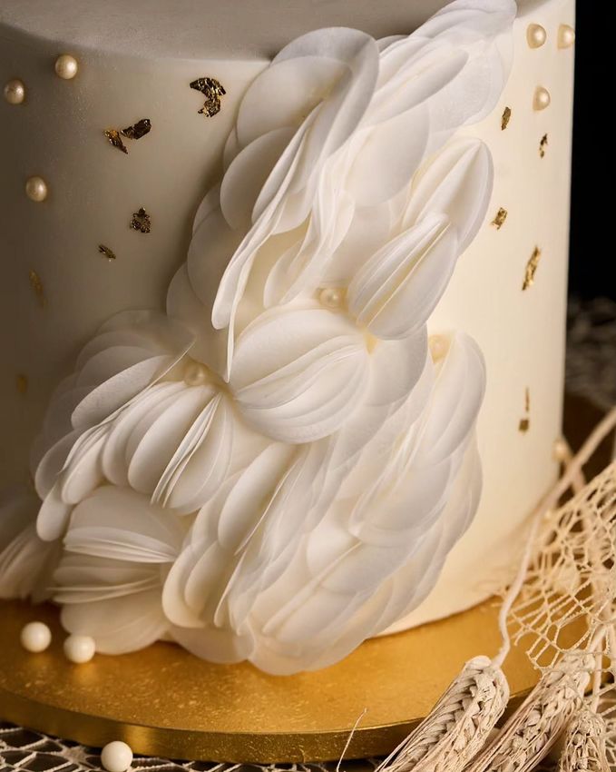 Torta decorata con nastro rosa e bianco, su un'alzata bianca.