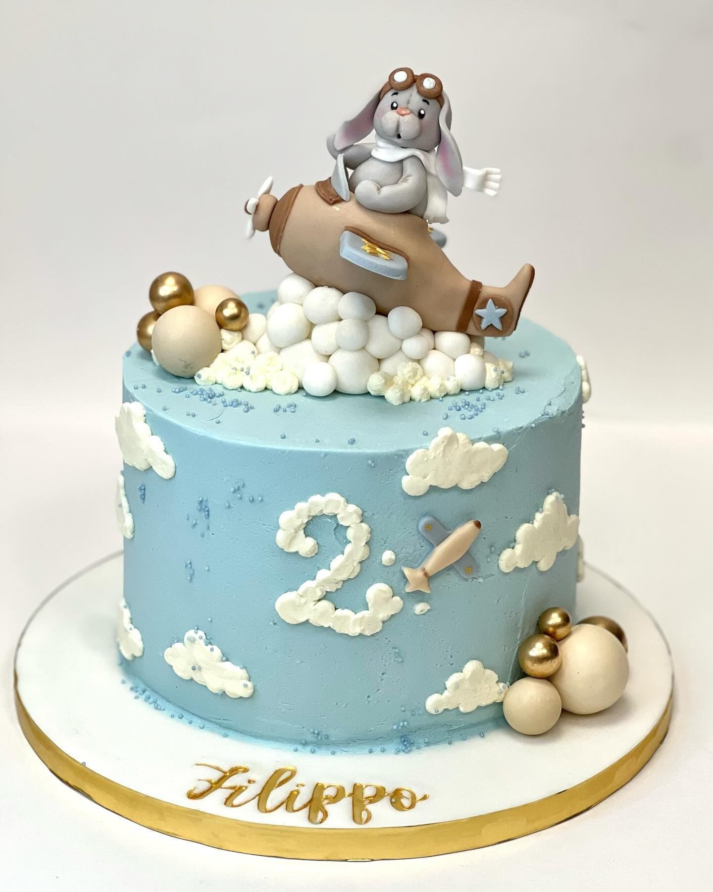 Torta con un coniglietto pilota su un aereo, glassa blu, nuvole e