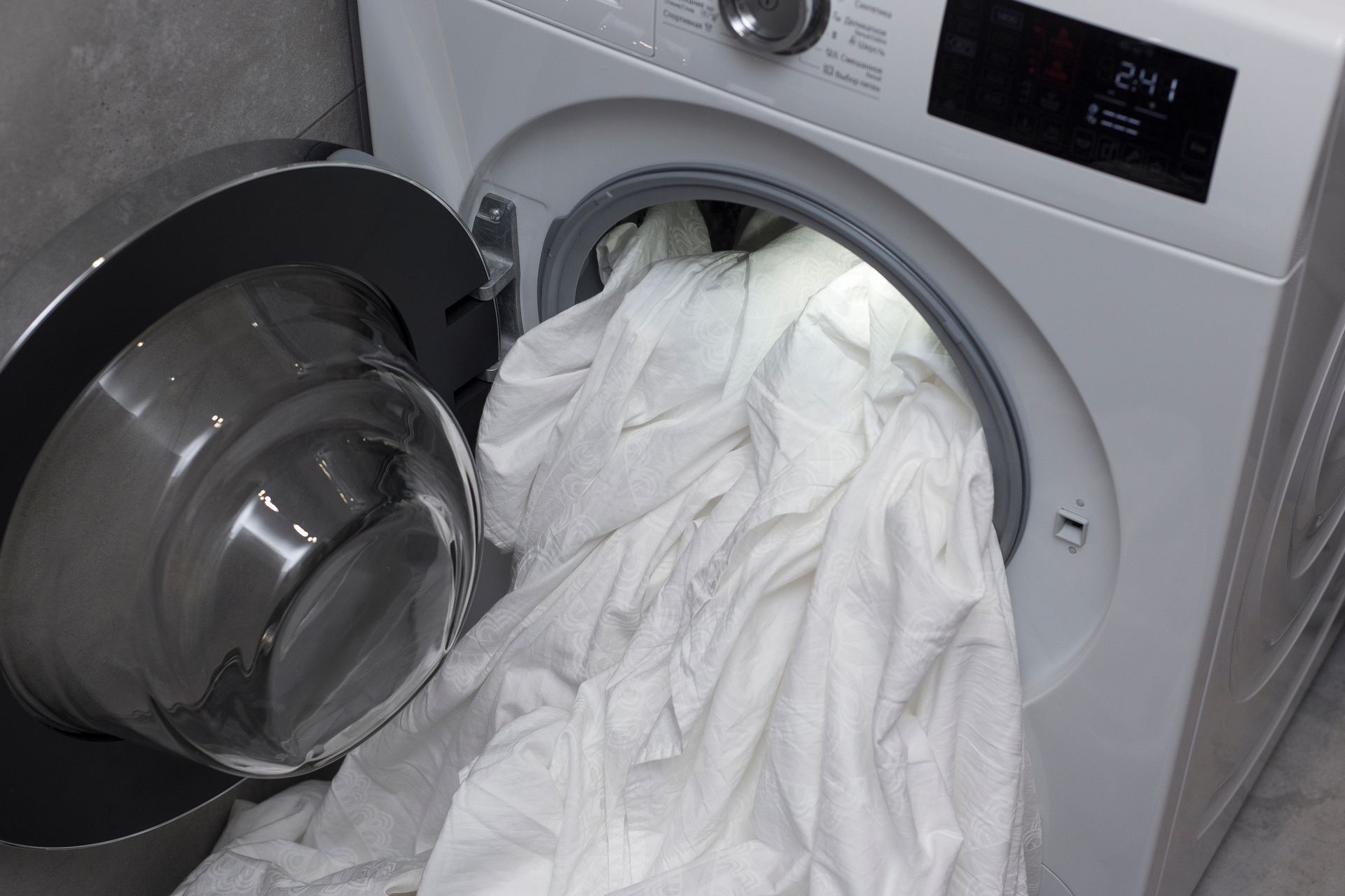 White Laundry Spilling Out of a Front-loading Washing Machine — Flynns Beach Service Laundry in Lighthouse Beach, NSW