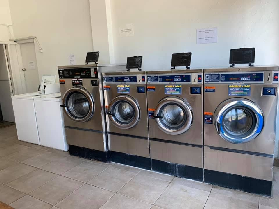 Row of Four Stainless Steel Front-loading Commercial Washing Machines — Flynns Beach Service Laundry in Port Macquarie, NSW