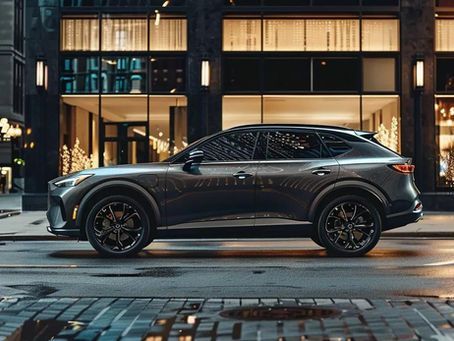 Dark gray SUV parked on a city street in front of a modern building with lights.