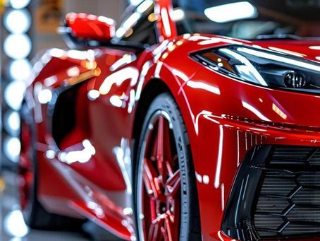 Red sports car, close-up view; shiny paint, black accents, red rims, bright headlights.