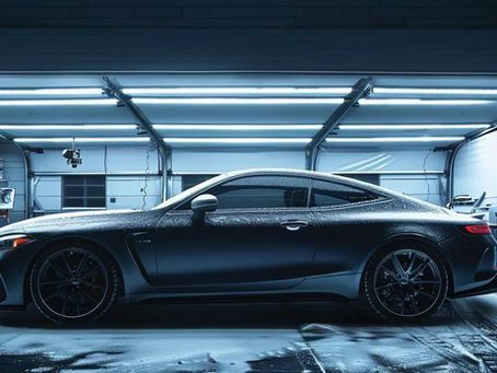 Dark coupe in a garage with blue lighting and wet floors.