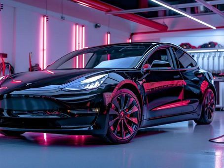 Black Tesla Model 3 parked in a garage with pink and blue neon lighting.