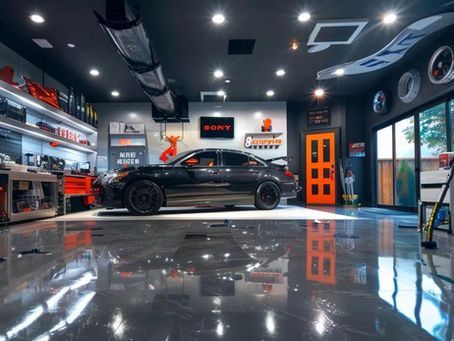 Black car in a modern, well-lit garage with polished floor, tools, and orange door.