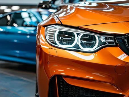 Orange sports car with white LED headlights, blue car in the background.