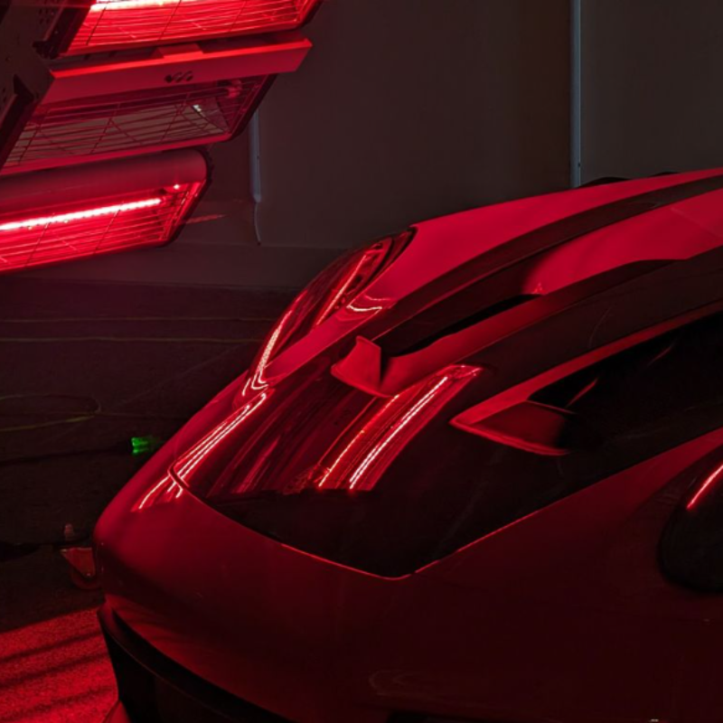Person in black glove applying ceramic coating on a shiny red car.