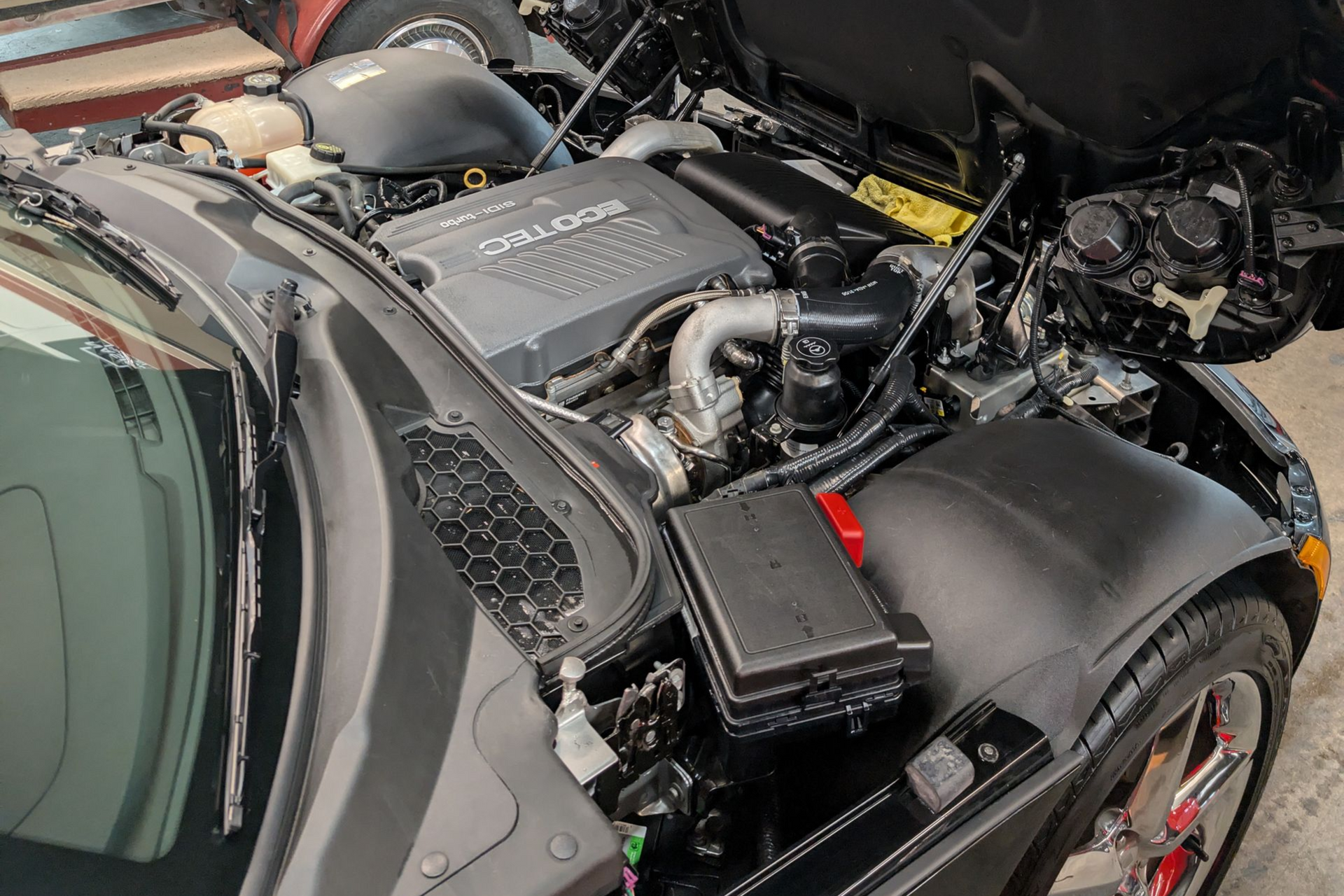 Black car engine bay, hood open, showing a detailed view of the engine and components.