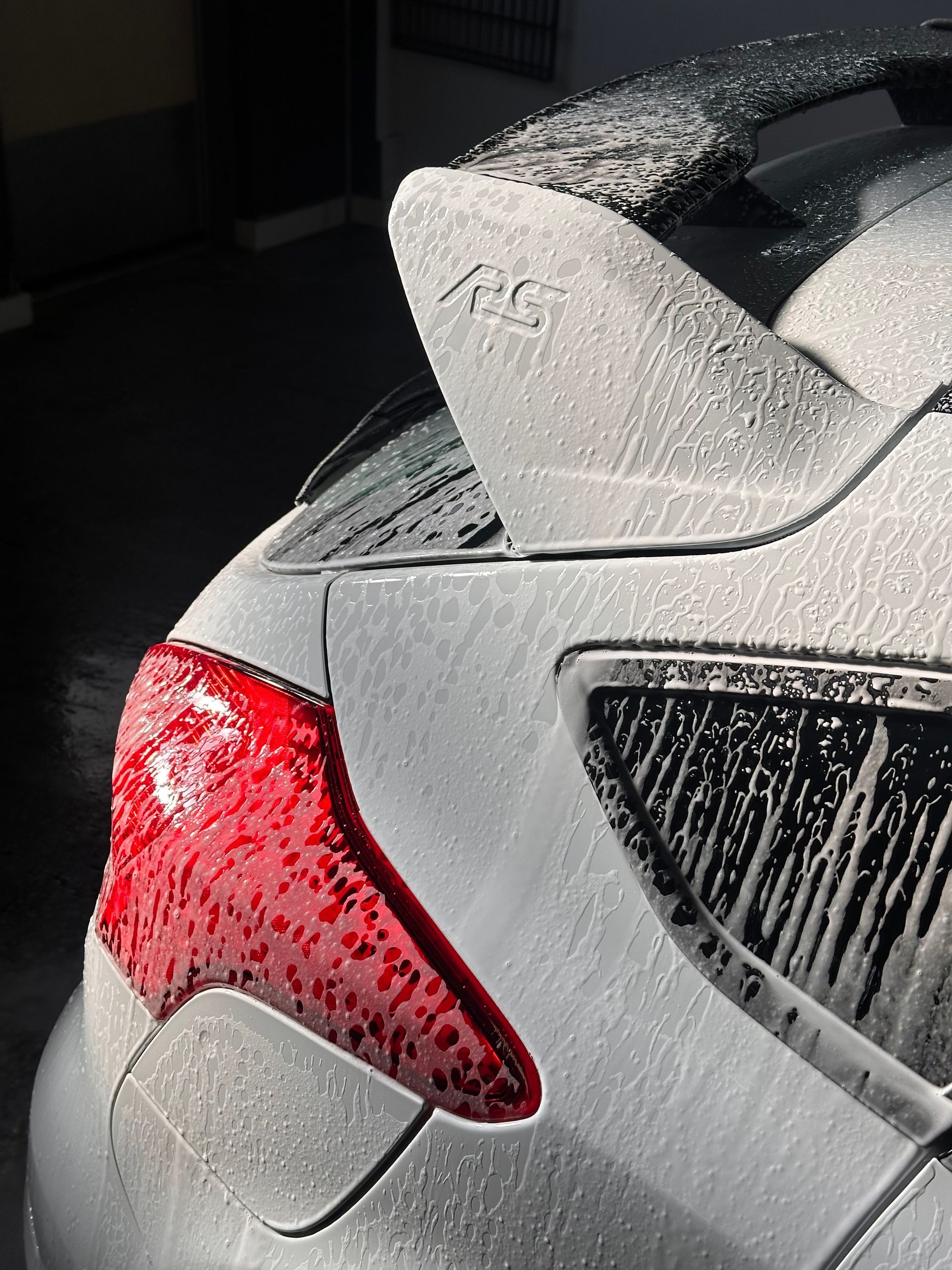 White car rear with red taillight covered in soap suds.
