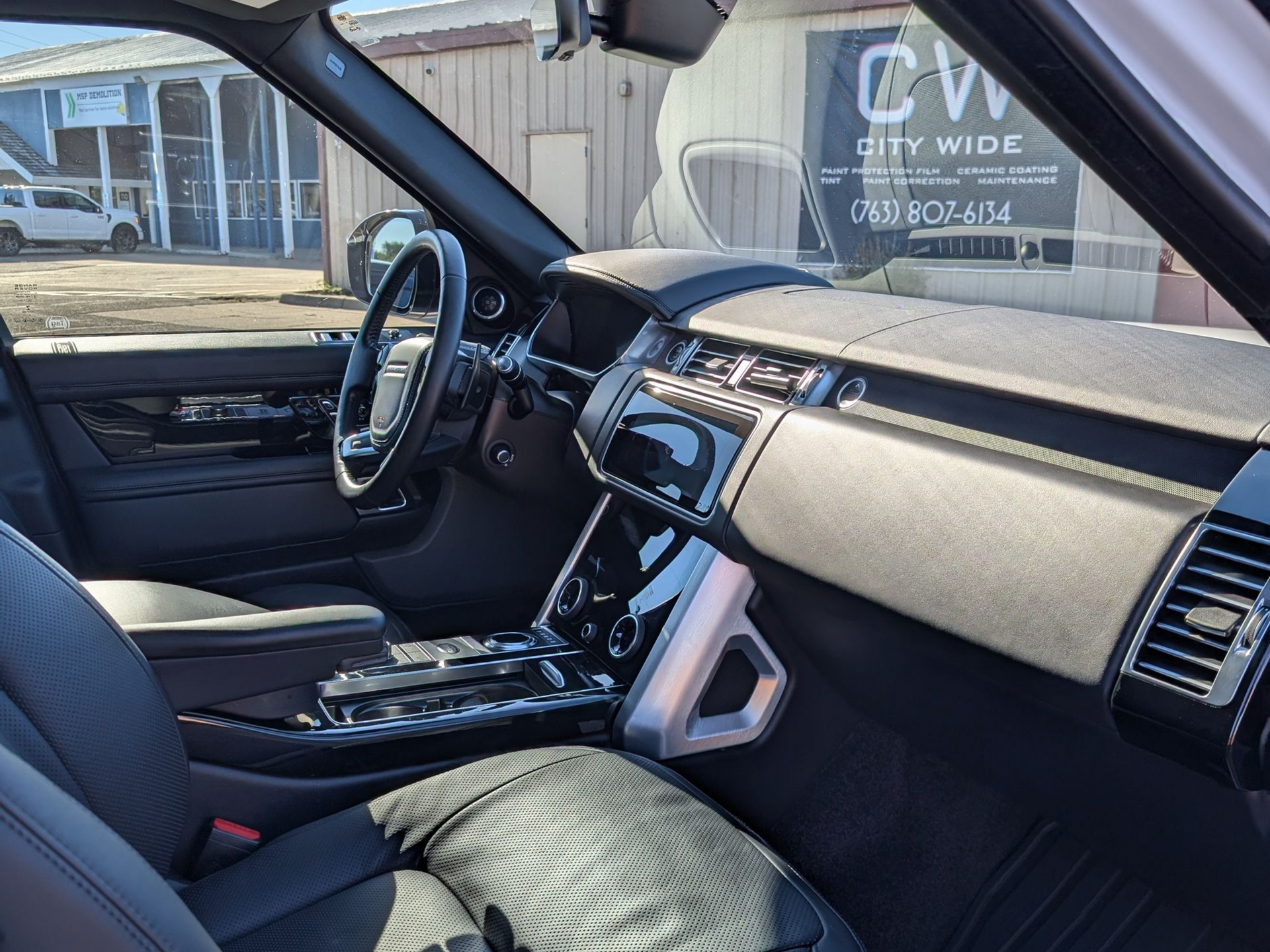 Interior view of a black Range Rover with leather seats, dashboard, and steering wheel.