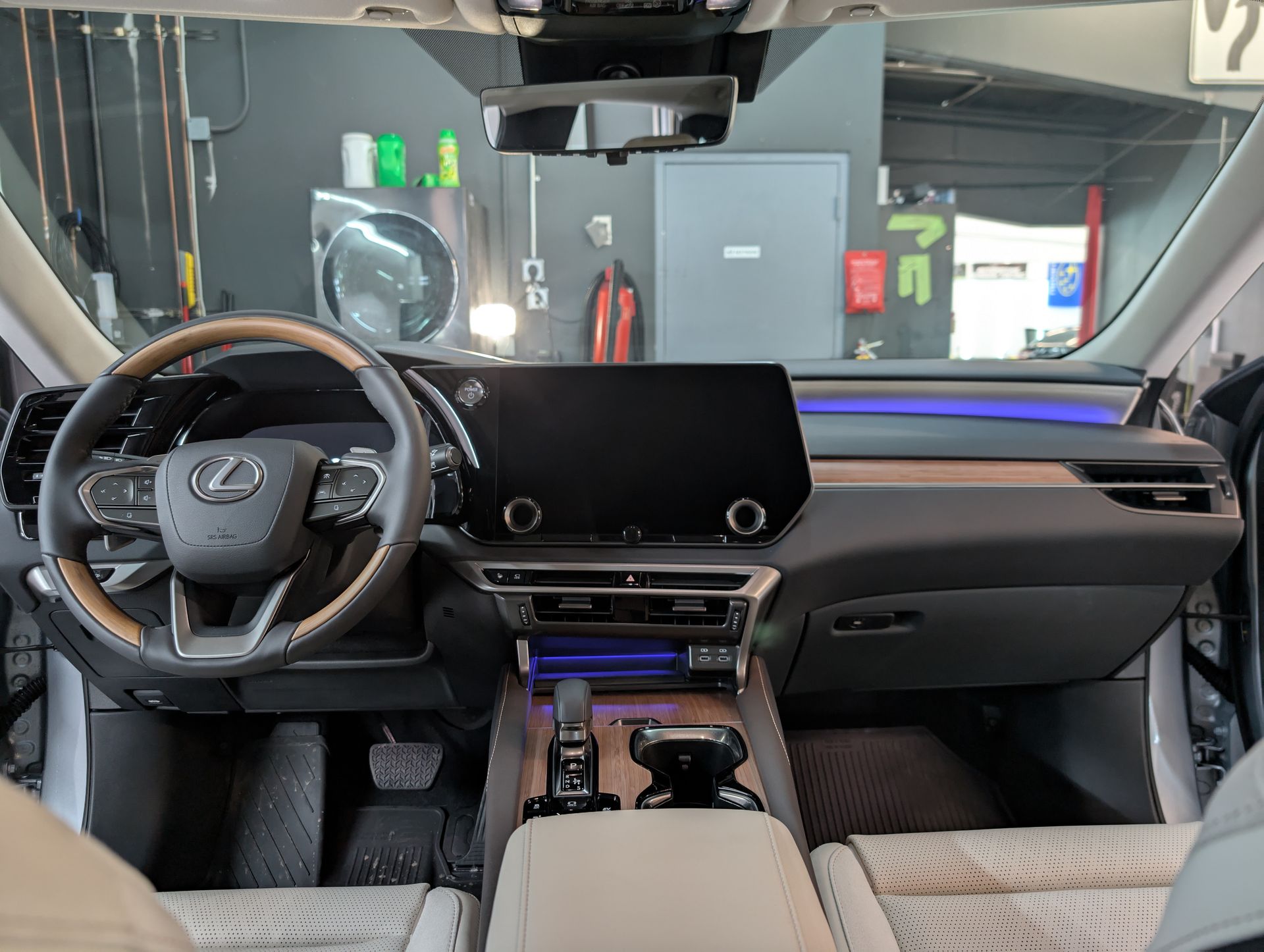 Interior view of a Lexus dashboard with infotainment screen, wood trim, and cream-colored seats.